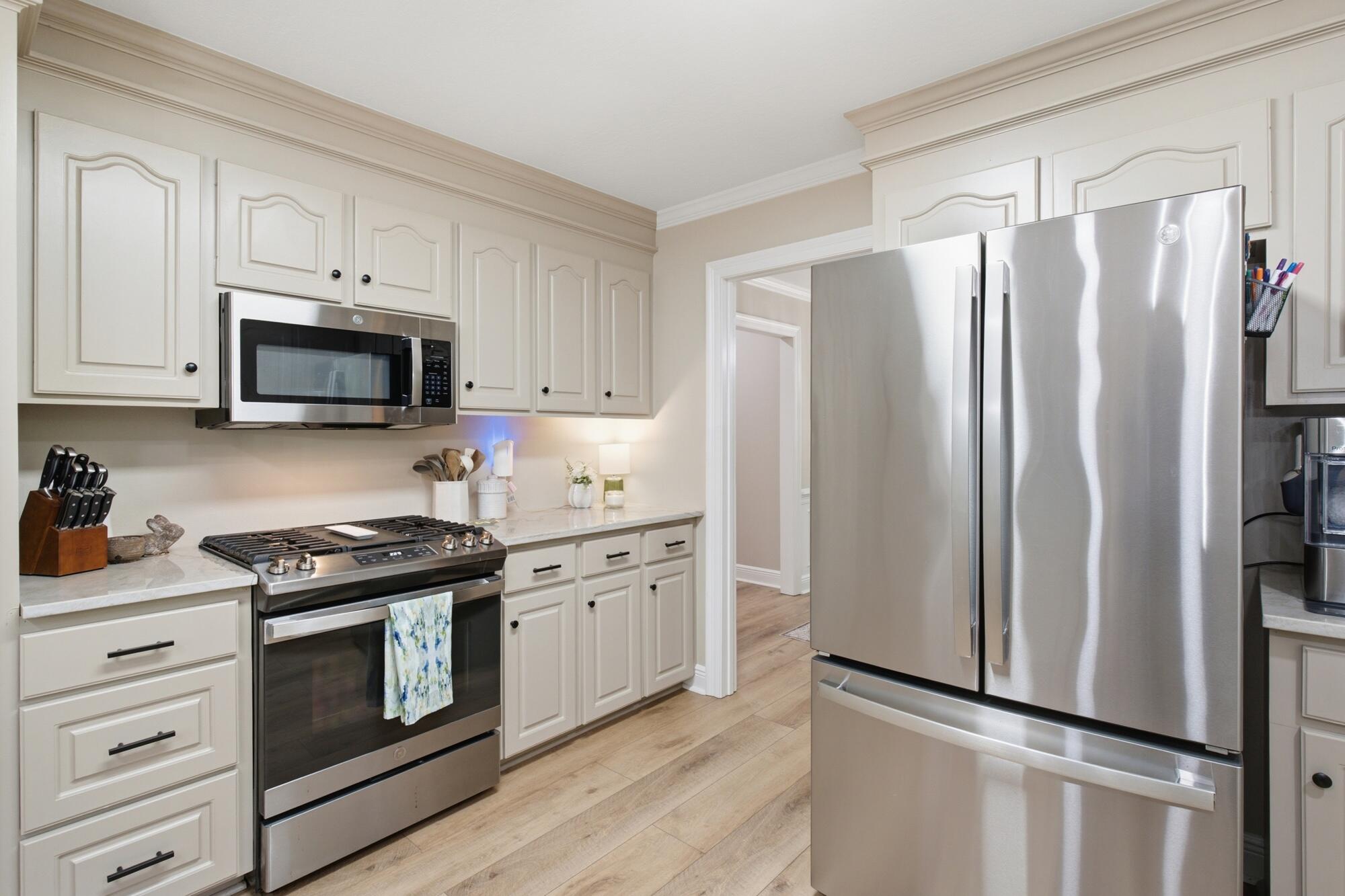 Kitchen with white cabinets, stainless appliances, a gas range, and light wood floors.