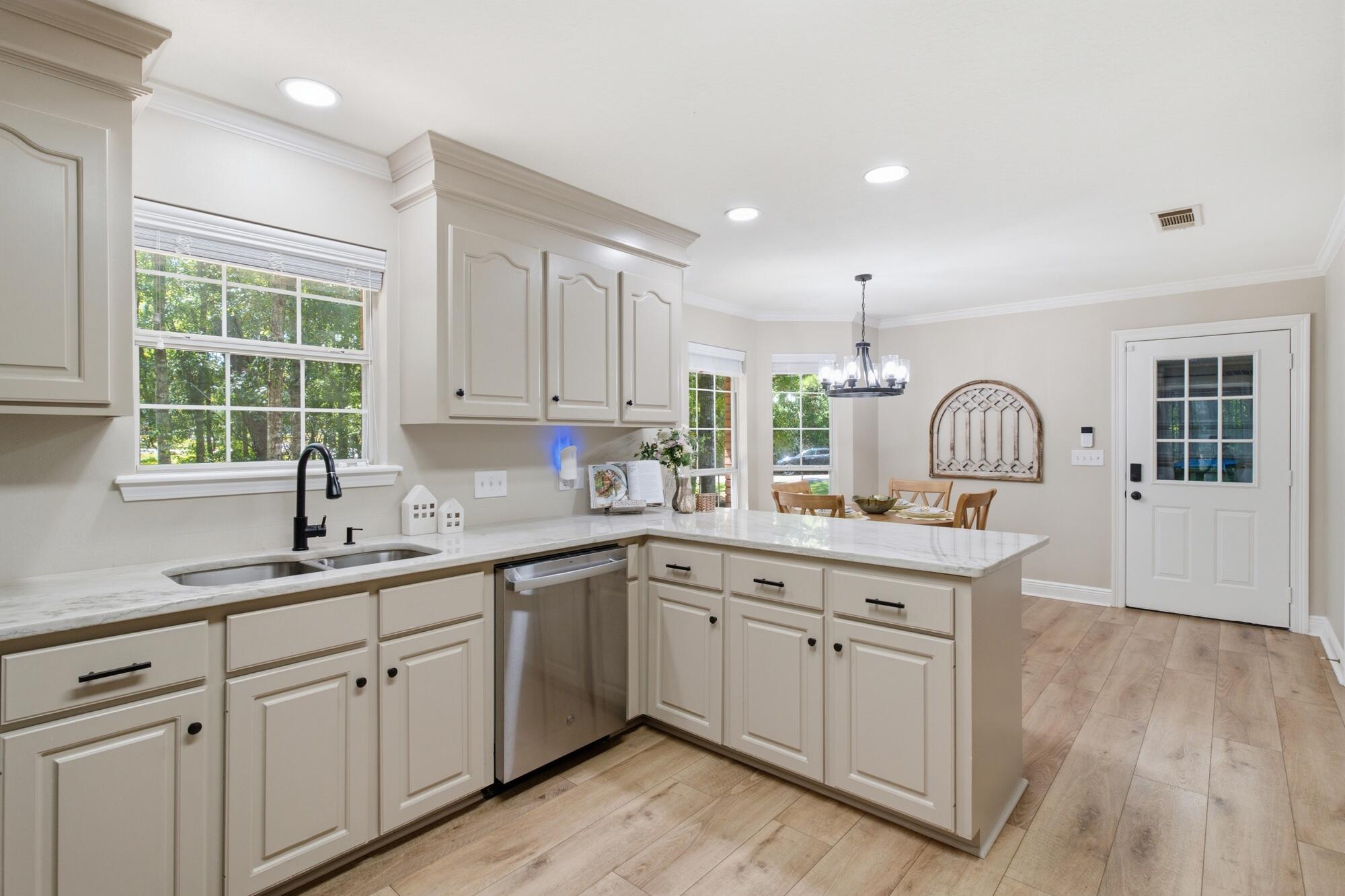 Bright kitchen with cream cabinetry, white stone counters, and a dining area beyond the island.