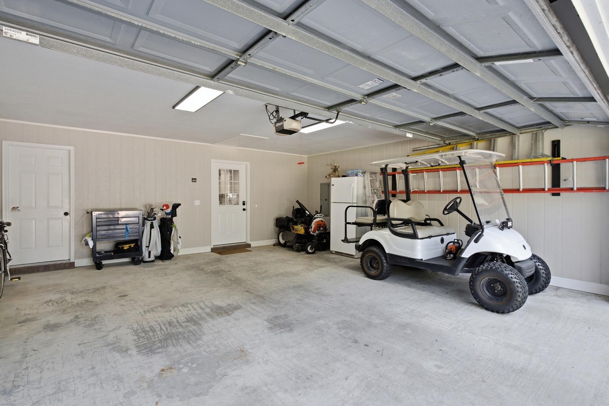Garage with a white golf cart, golf bags, and a tool chest.