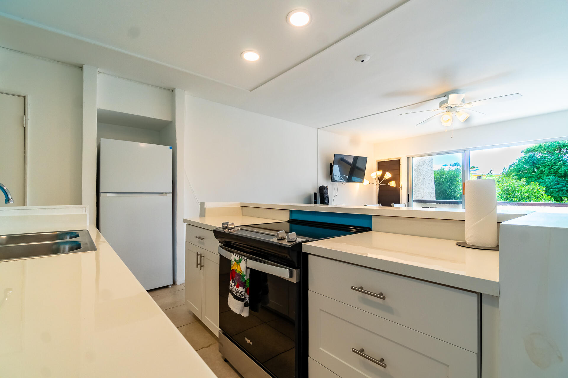 Kitchen with white counters, black range, and sliding glass doors overlooking greenery.