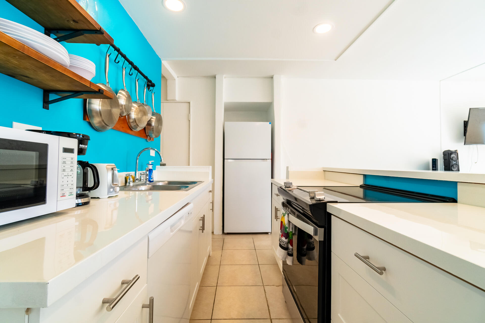 Kitchen with turquoise walls, white counters, and open shelves displaying dishes and cookware.