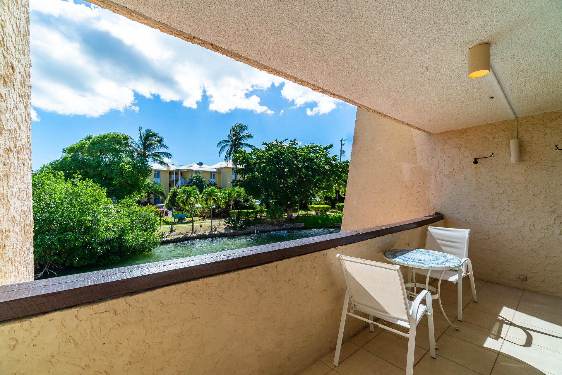 Covered balcony with white seating overlooking a waterway and tropical greenery.