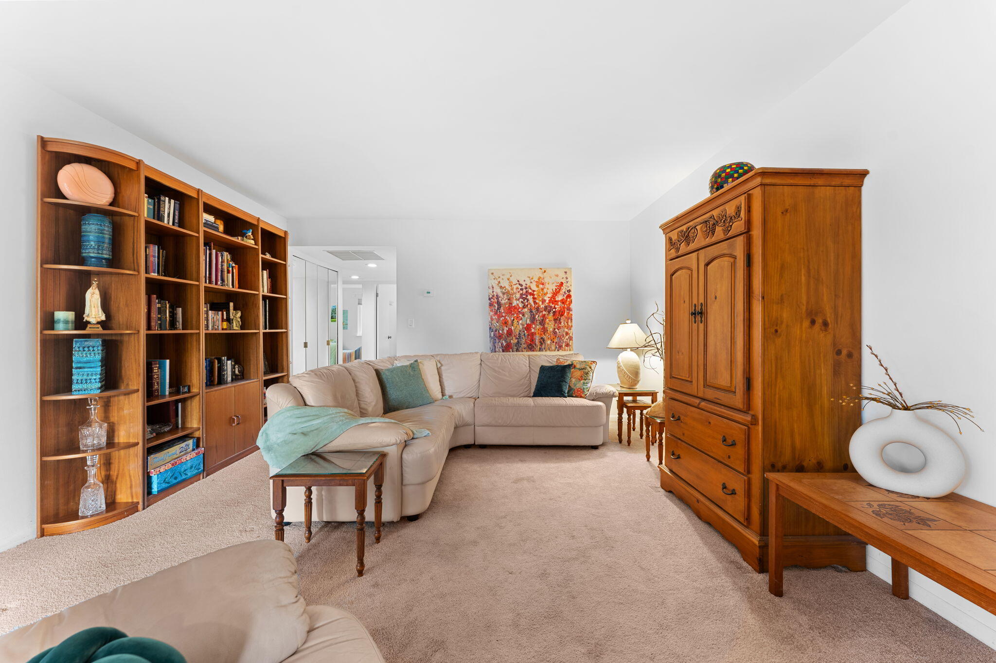 Living room with built-in bookshelves, a beige sectional, and a large wooden armoire.