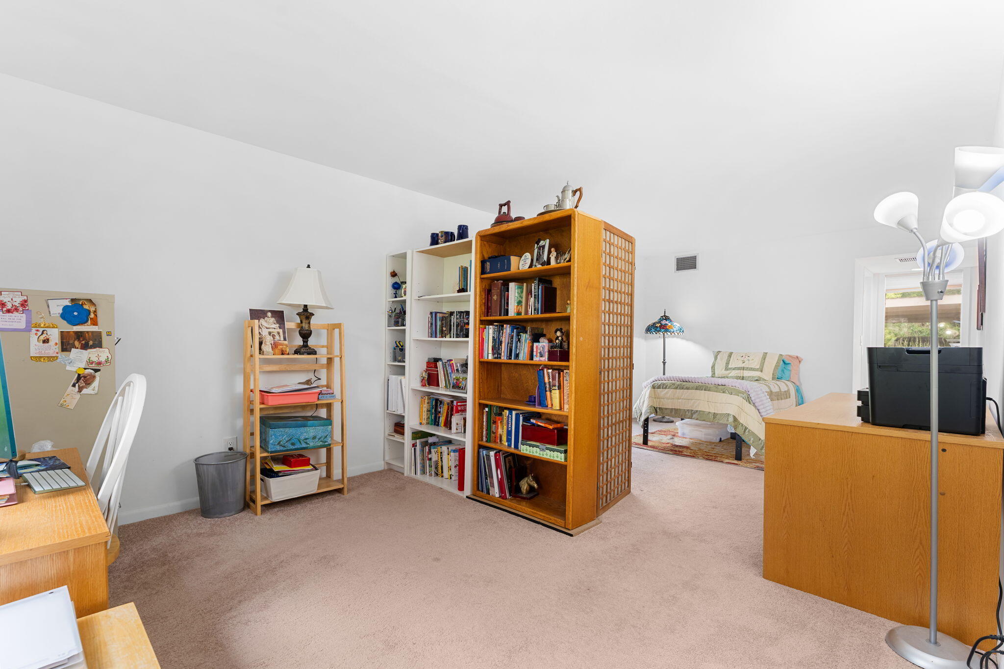 Carpeted bedroom with a bed, tall bookcases, and a desk.