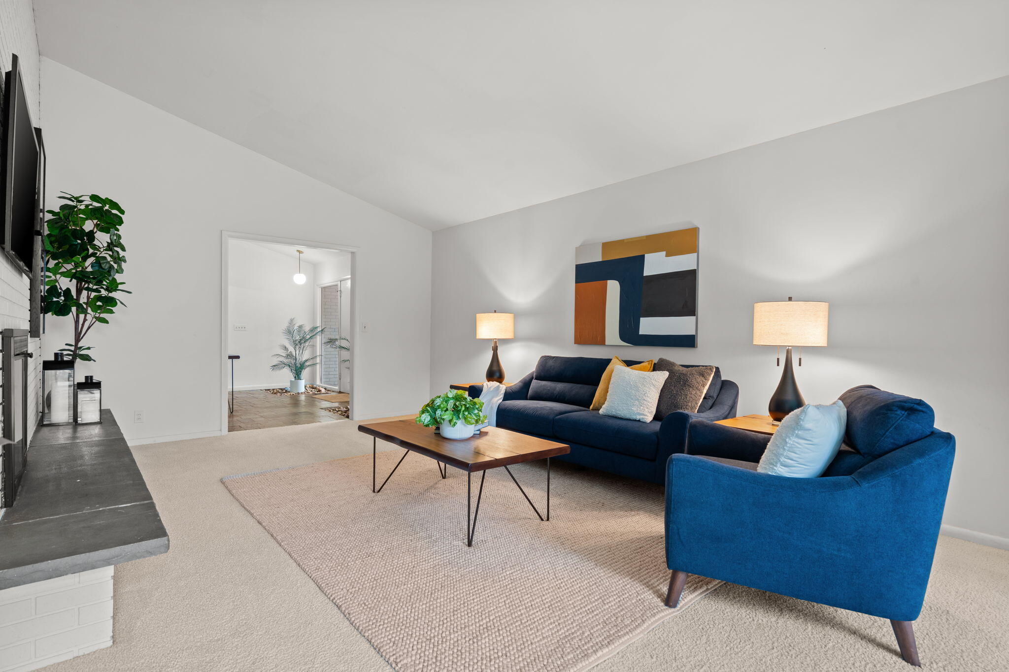 Staged living room with blue sofas, a wood coffee table, and abstract artwork.