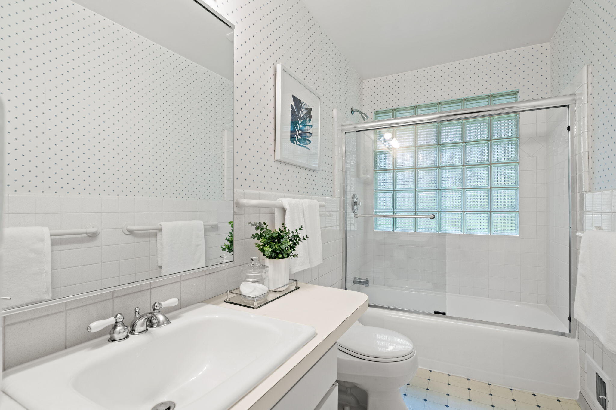 Bathroom with glass-block shower window, white tile, and a long vanity.