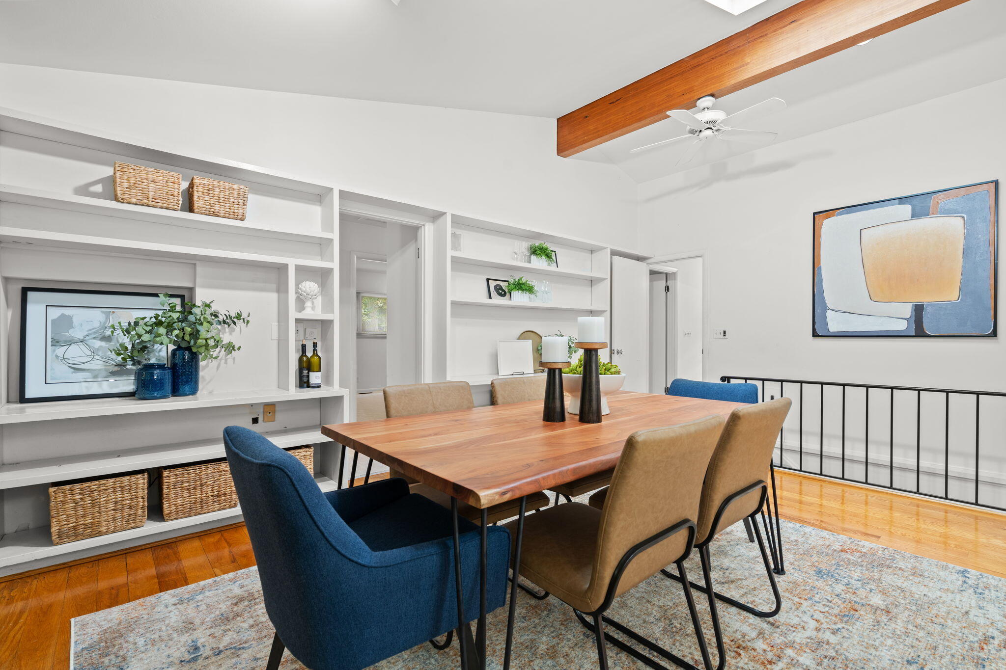 Dining room with built-in white shelves, a wood table, and an exposed ceiling beam.