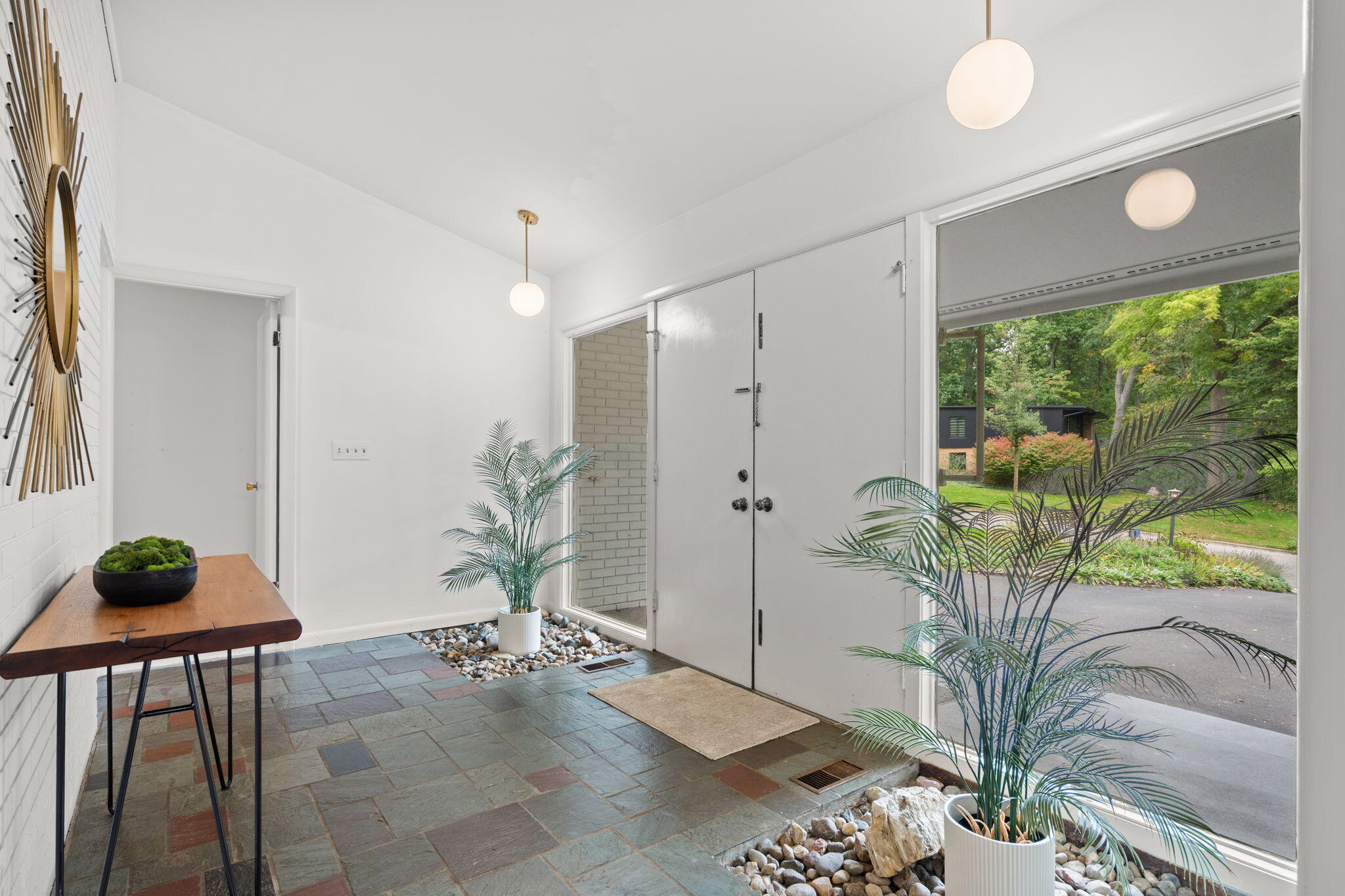Entry foyer with slate flooring, white double doors, and a glass opening to the landscaped yard.
