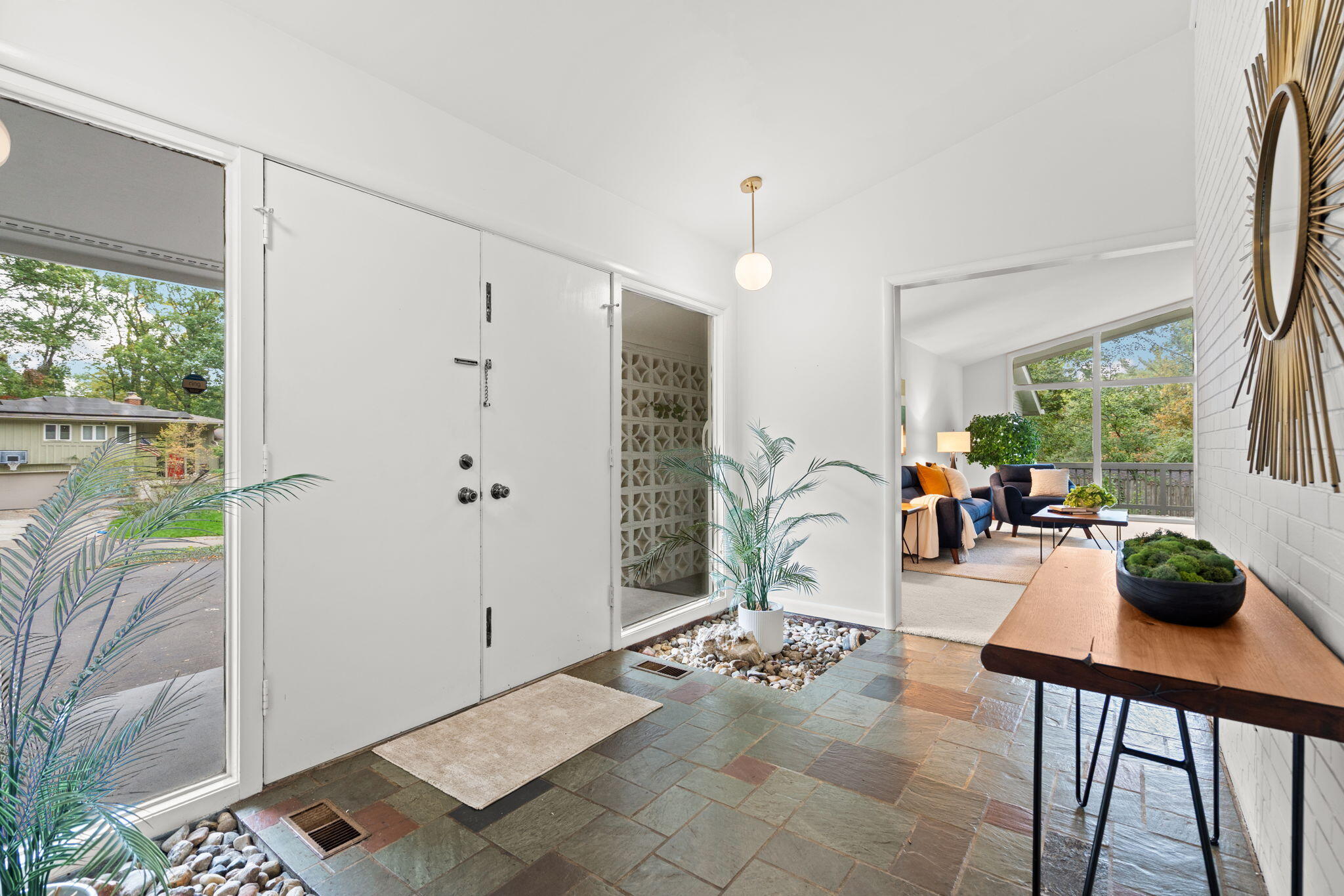 Furnished entry foyer with slate tile, white double doors, and a pebble-lined planter.