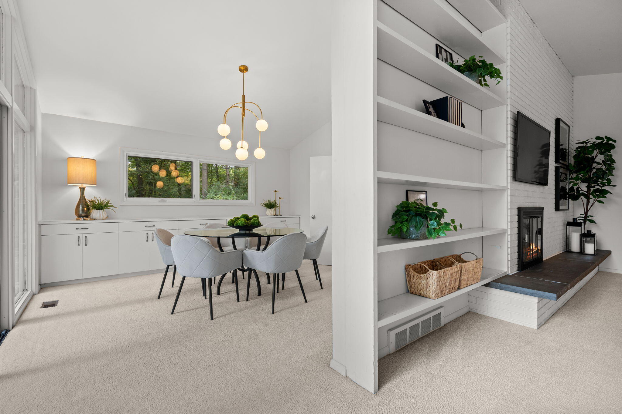 Dining area with a round table beside built-in shelving and a fireplace.