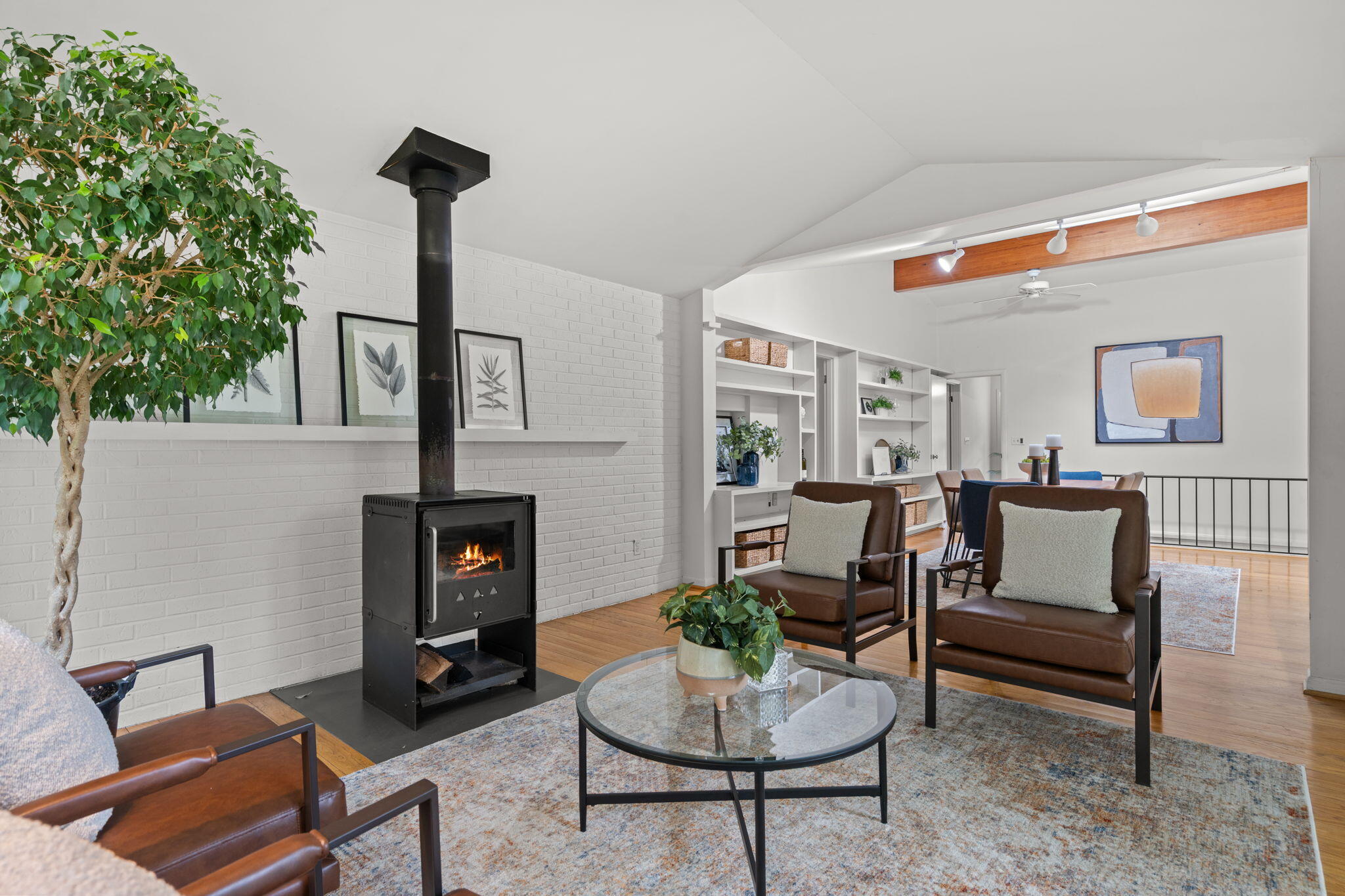 Living room with a black wood stove, brown leather chairs, and an open dining area.