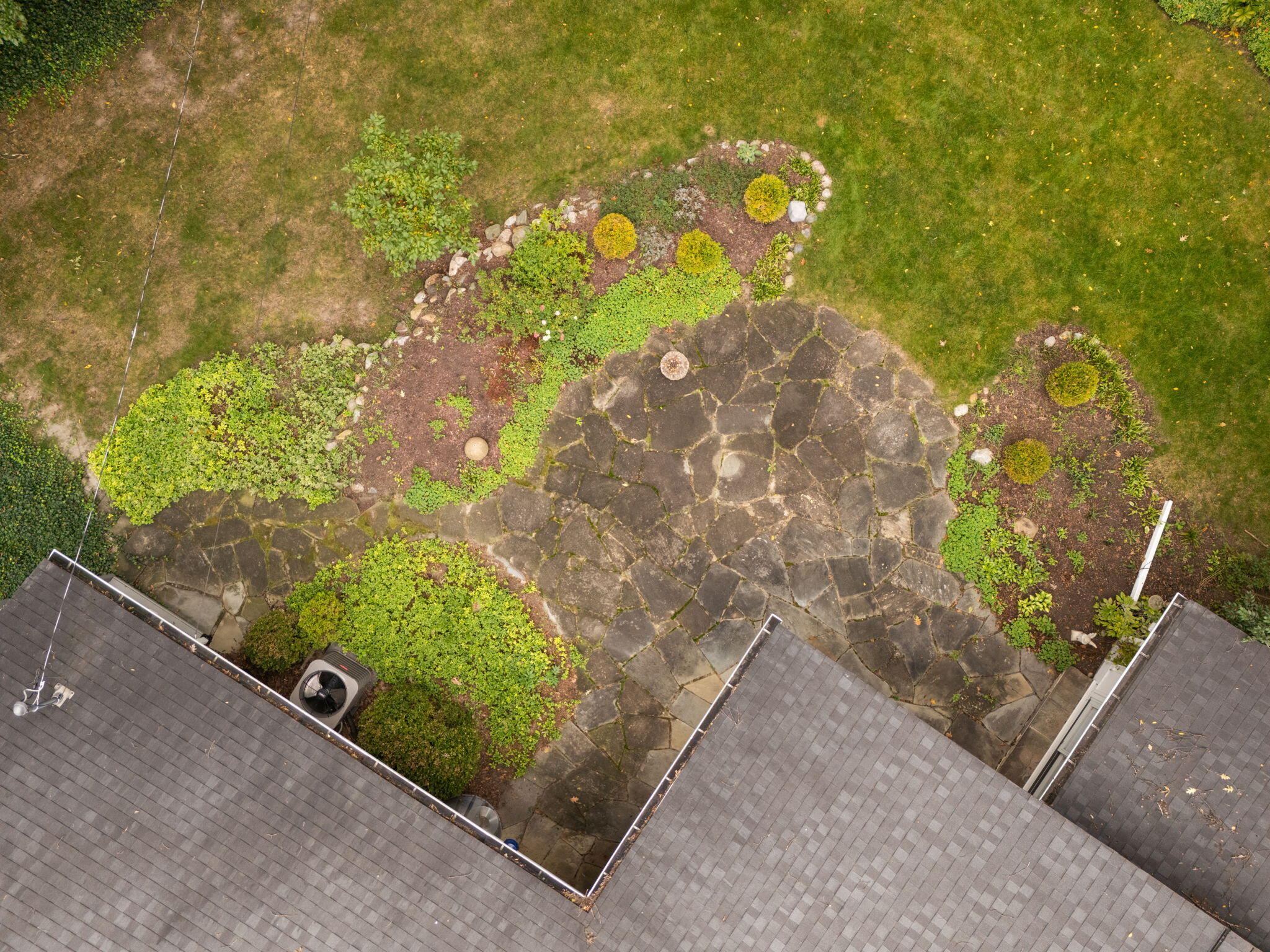 Aerial view of a stone patio bordered by landscaped garden beds and lawn.