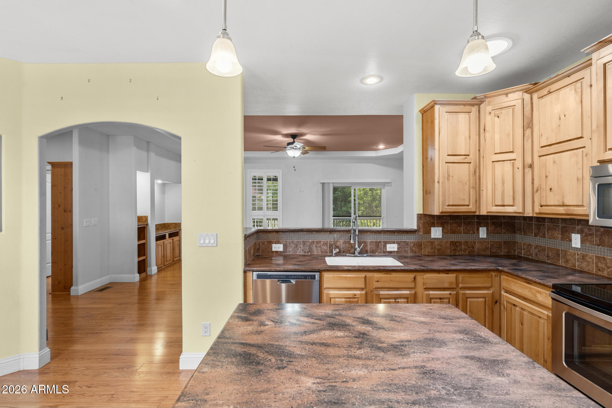 Kitchen with honey-toned wood cabinets, brown tile counters, and a large island in the foreground.