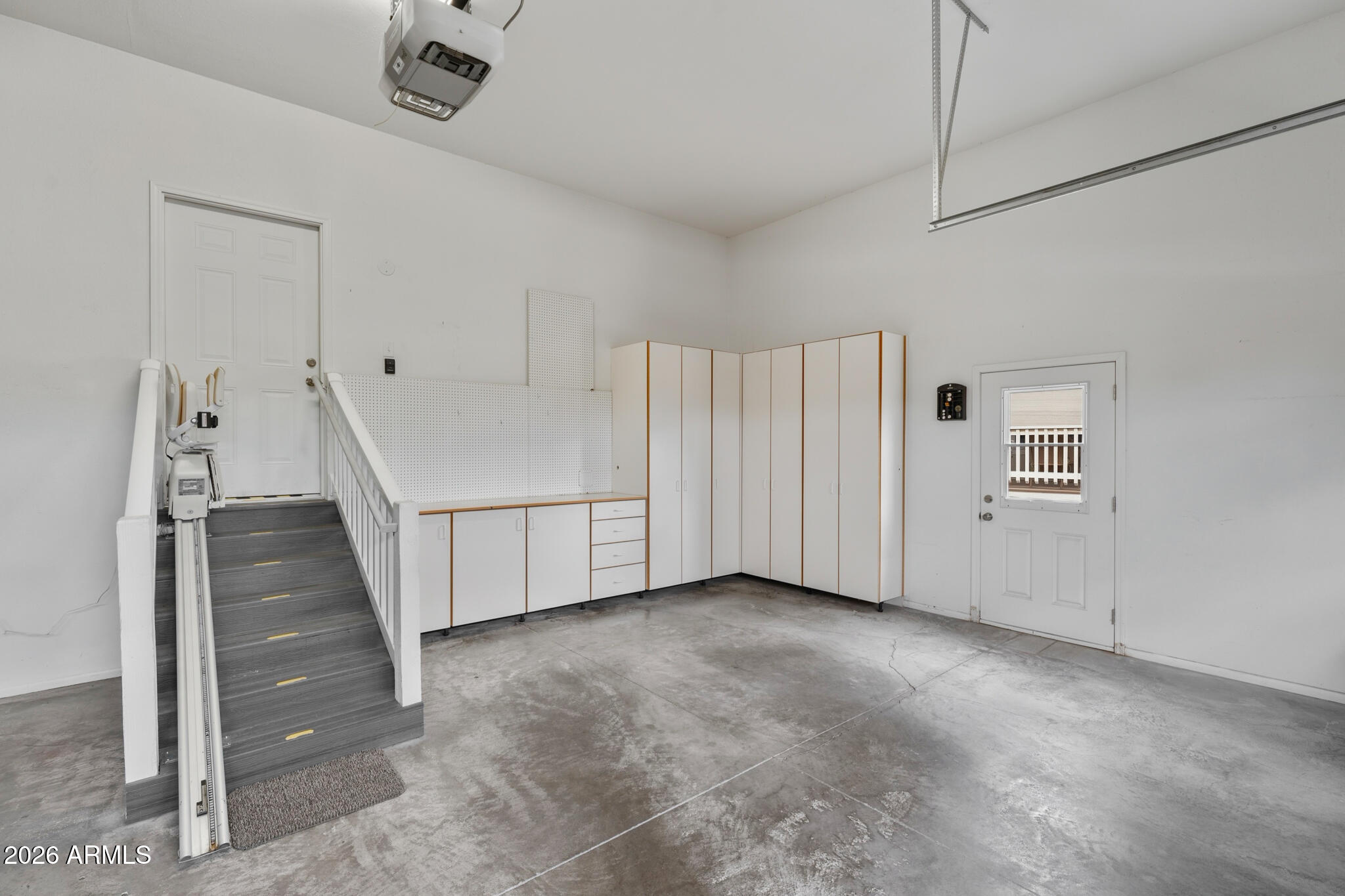 Garage with built-in storage cabinets, concrete flooring, and a stair lift beside the steps.