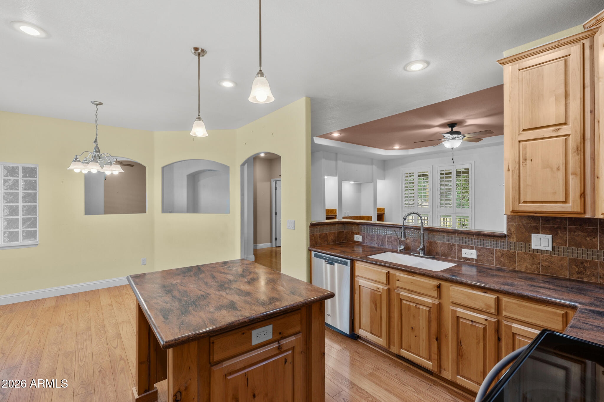 Kitchen with a large brown island, honey-colored wood cabinets, and plantation shutters.