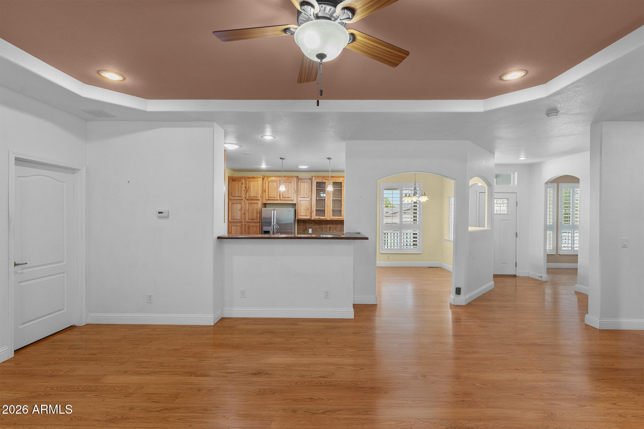 Open-plan living area with wood floors, a kitchen breakfast bar, and shuttered windows.