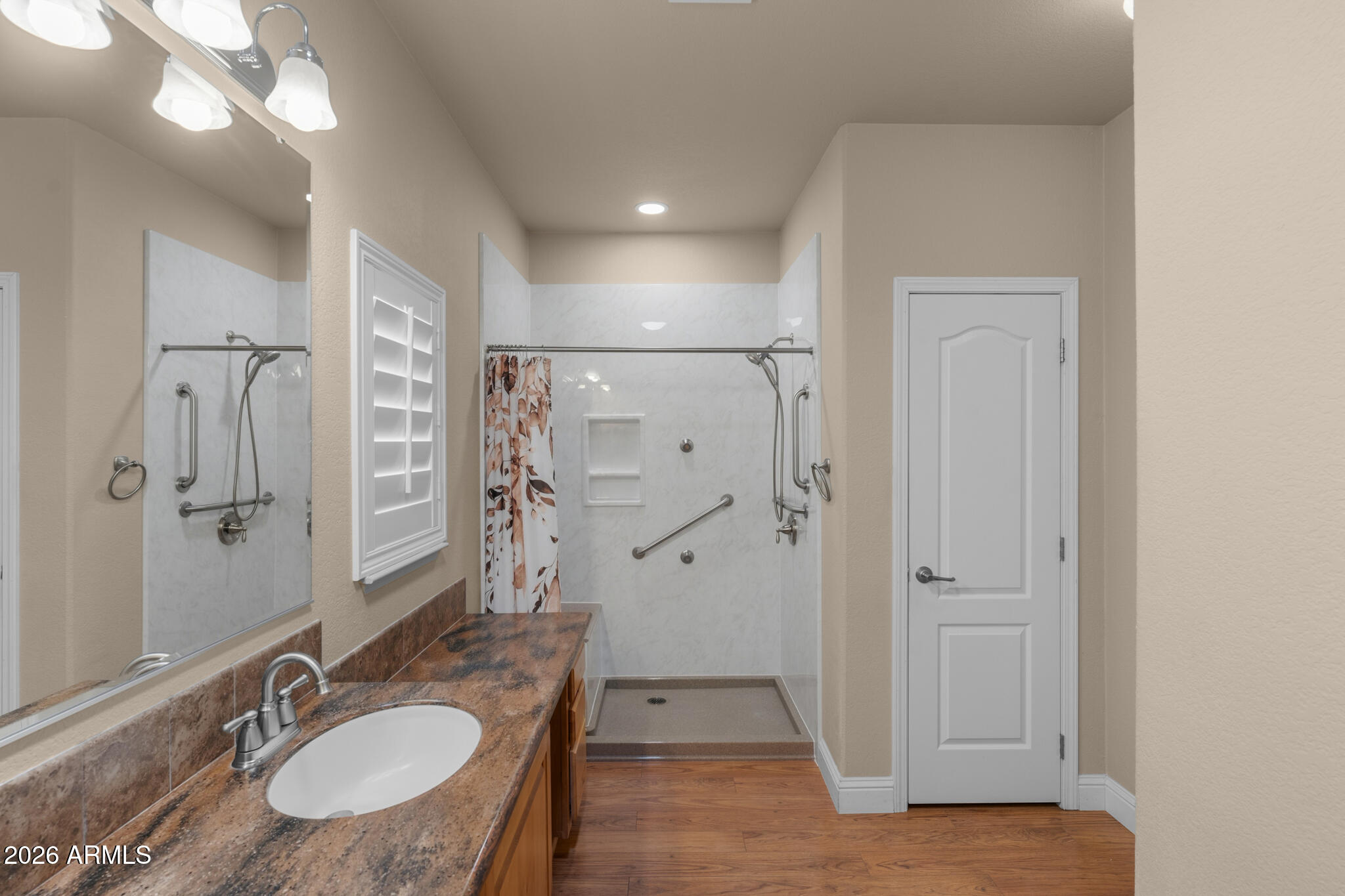 Bathroom with a wood-look vanity and accessible walk-in shower with grab bars.