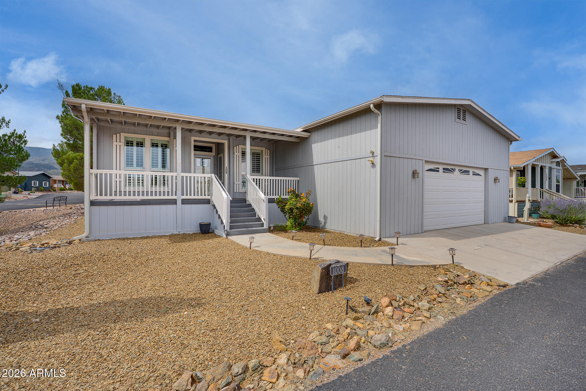 Gray home with a covered porch, front steps, and attached garage.
