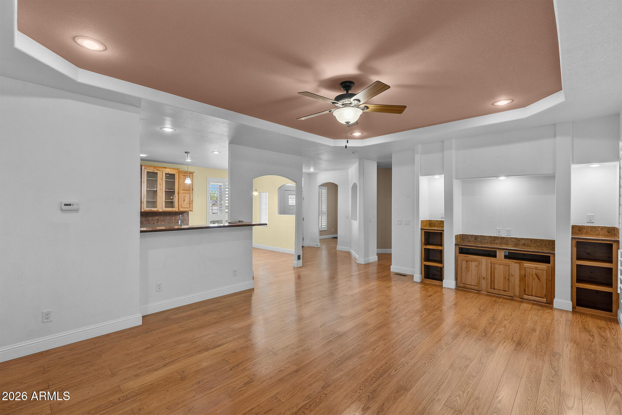 Open living area with wood flooring, built-in cabinetry, and a ceiling fan.