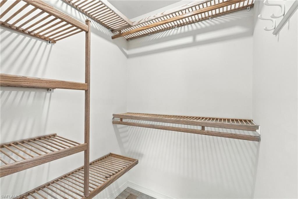 Walk-in closet with wooden slatted shelving on the walls and overhead.