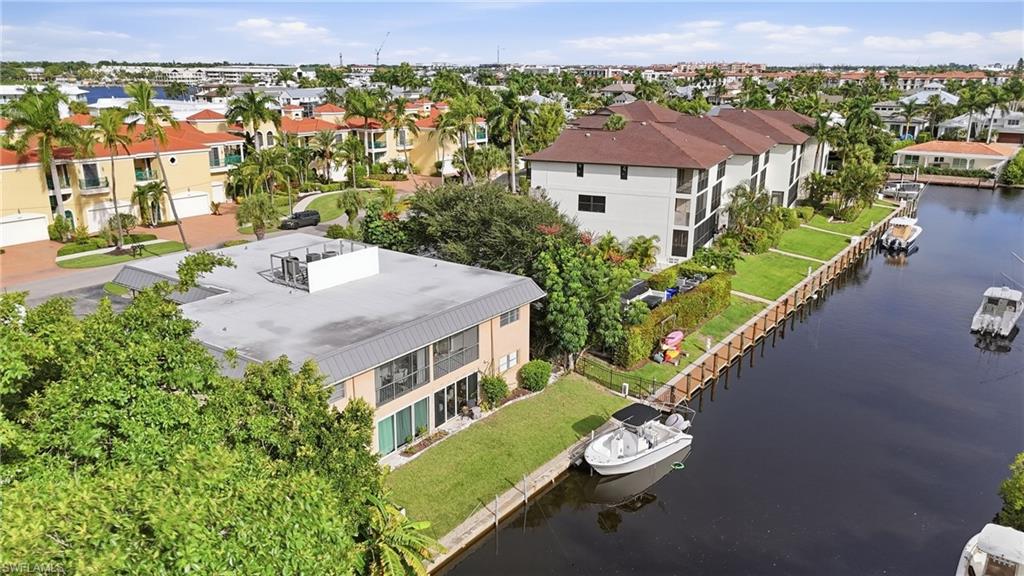 Aerial view of waterfront condominiums and boats along a palm-lined canal.