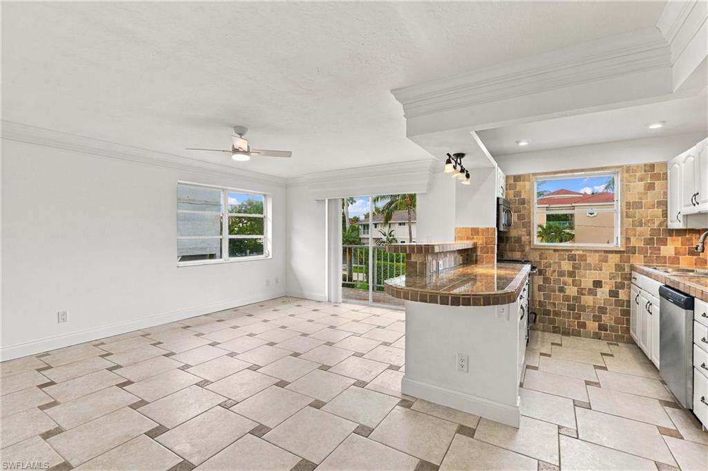Open-plan kitchen and dining area with tiled floors, breakfast bar, and balcony access.