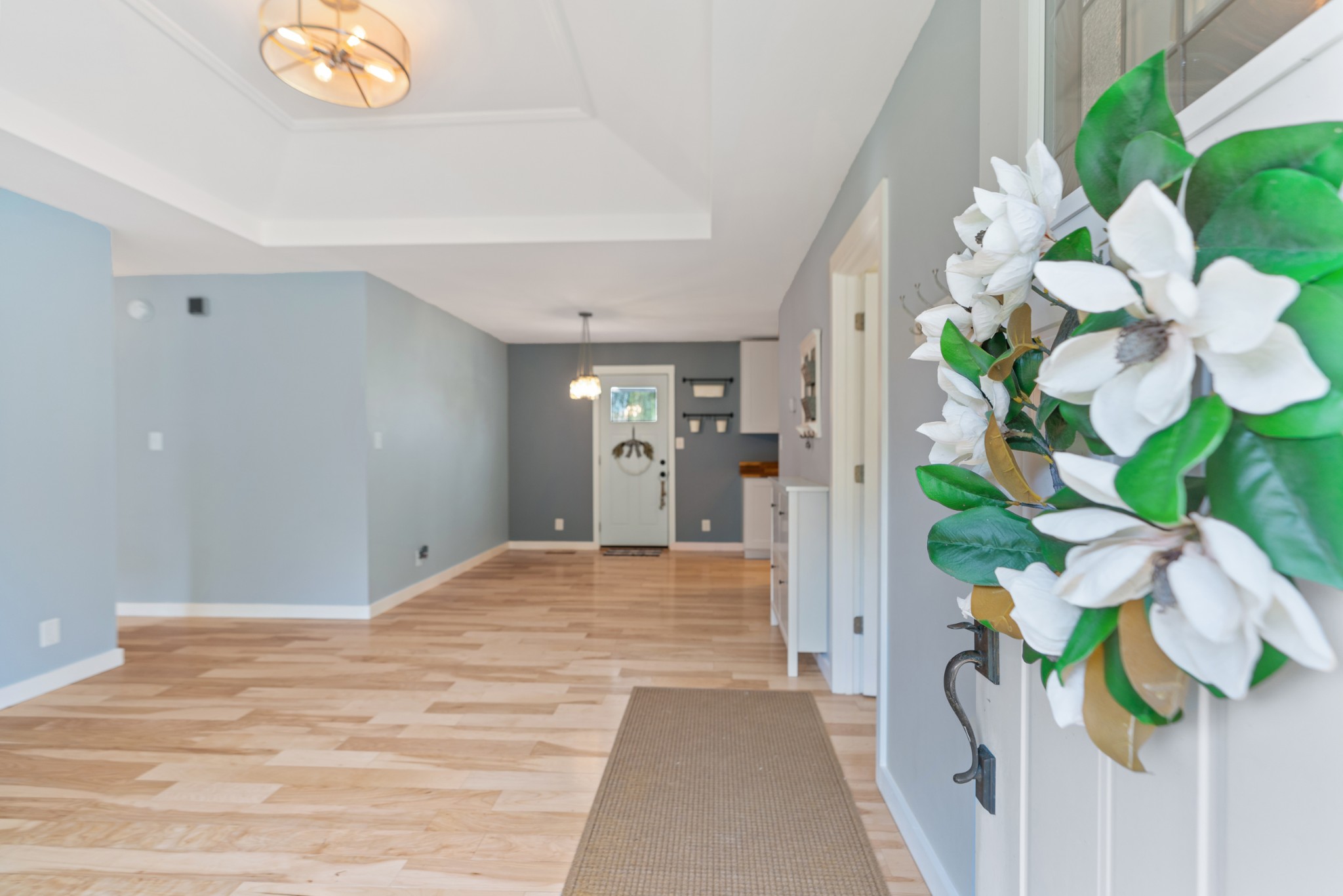 Entryway with light wood-look flooring, a woven runner, and a white front door.