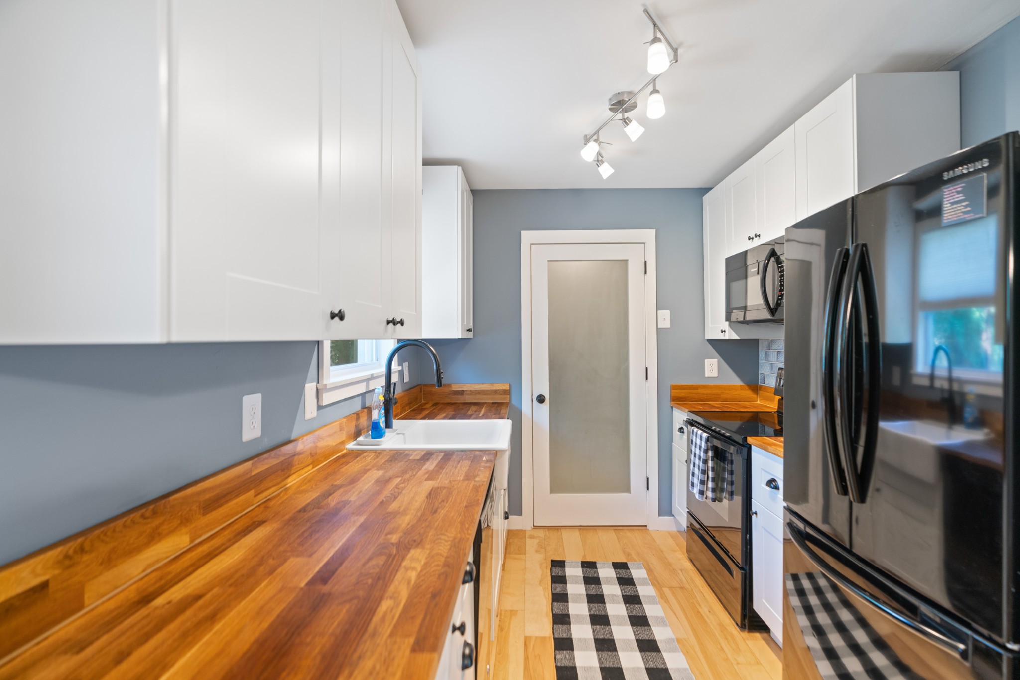 Kitchen with warm wood countertops, white cabinets, and stainless steel appliances.
