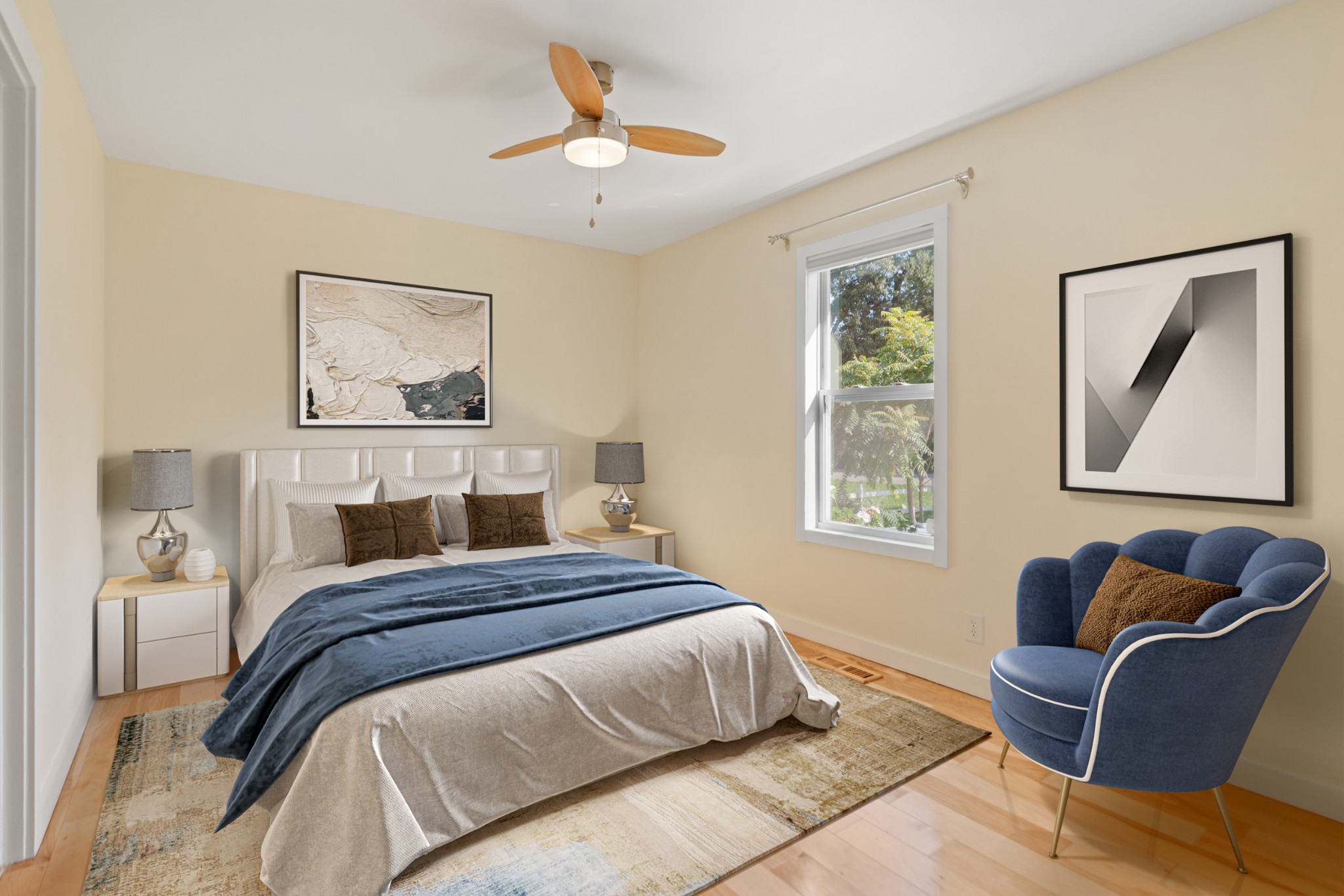 Staged bedroom with a king-size bed, navy bedding, and a blue armchair beside the window.