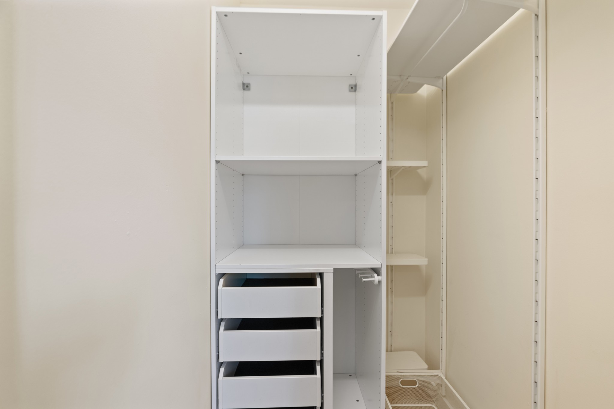 Built-in closet with white shelves, open drawers, and a mirrored panel.