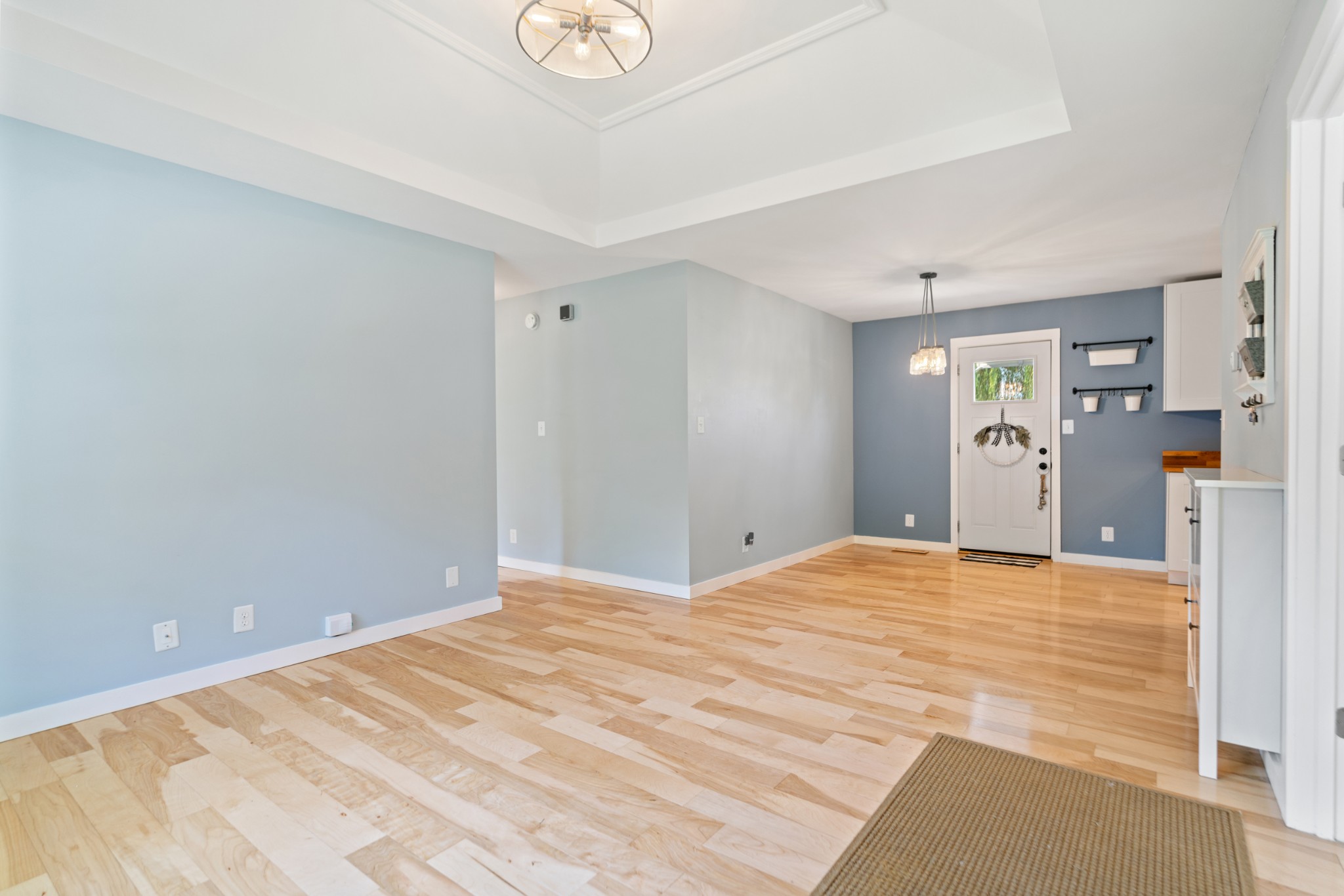 Open entry with pale blue walls, light wood floors, and a white front door.