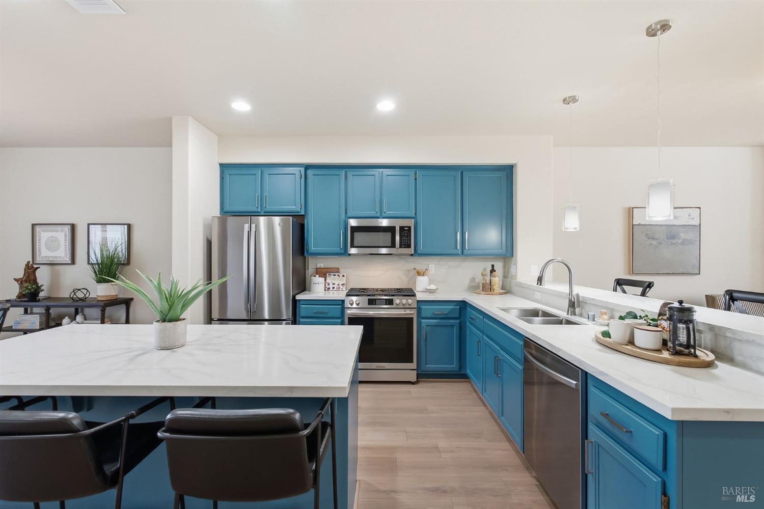 Kitchen with blue cabinets, white countertops, a large island, and stainless steel appliances.