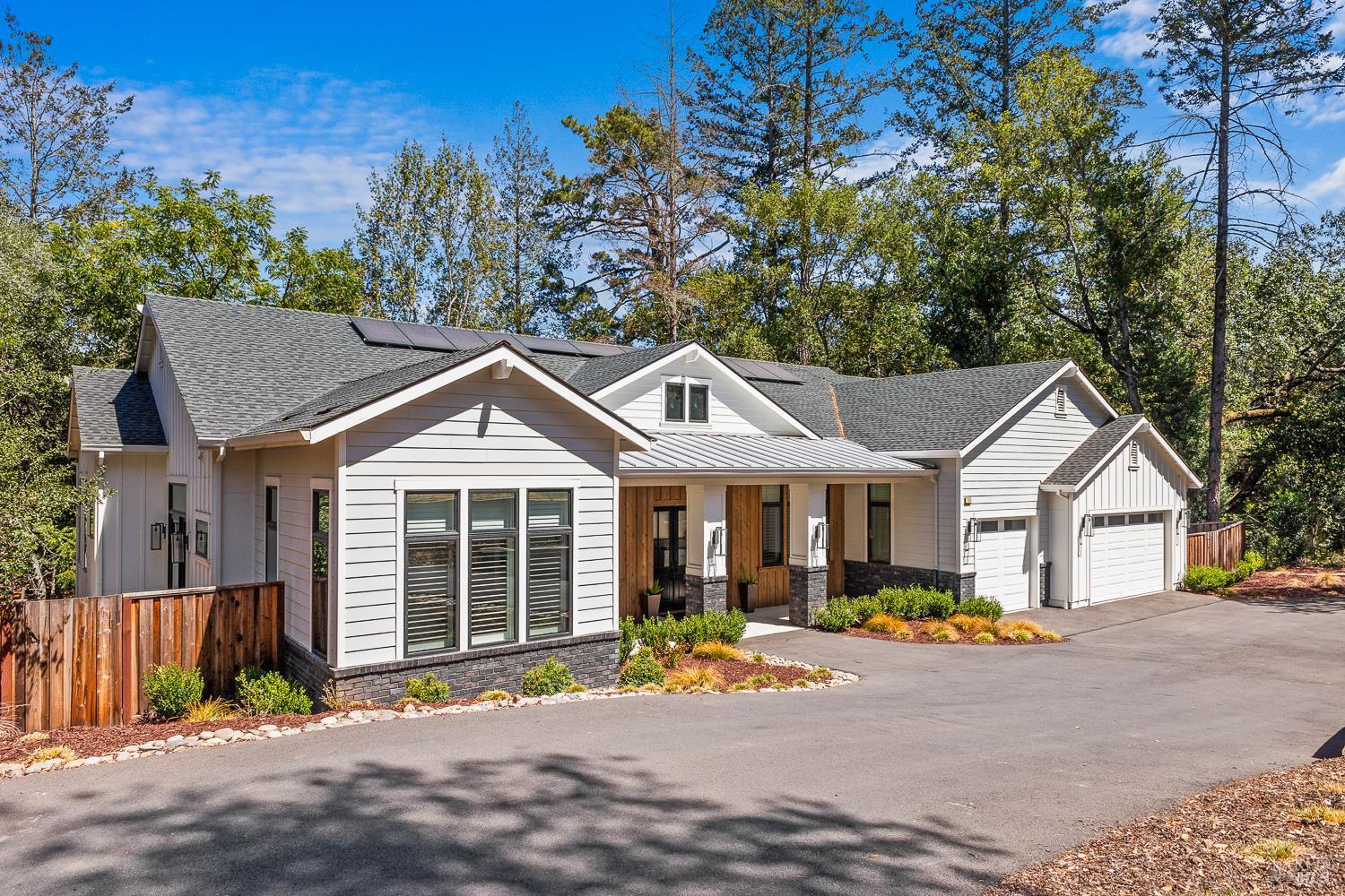 Modern white house with solar panels, a covered wood-entry porch, and an attached two-car garage.