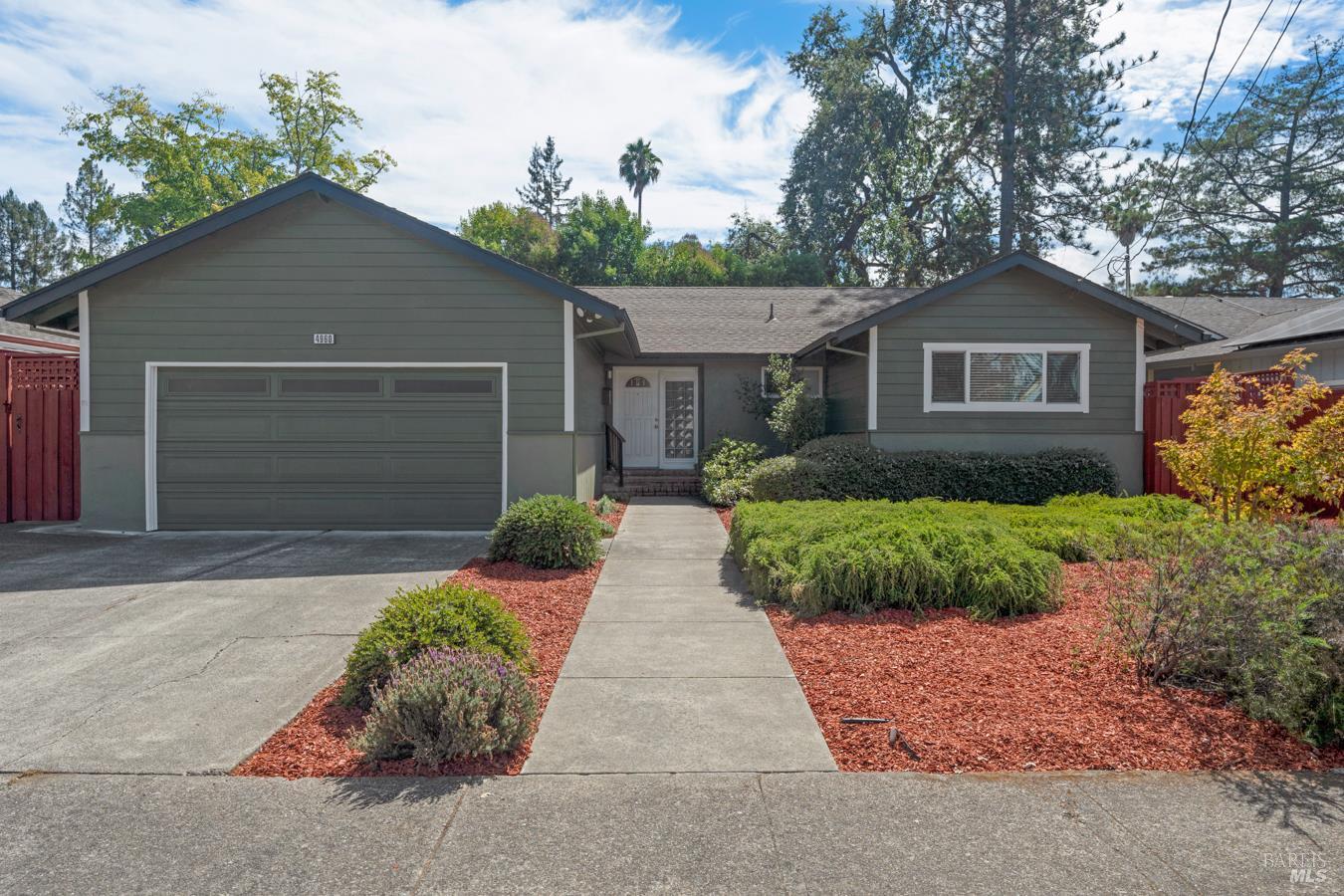 Gray single-story home with a two-car garage, red gates, and landscaped front yard.