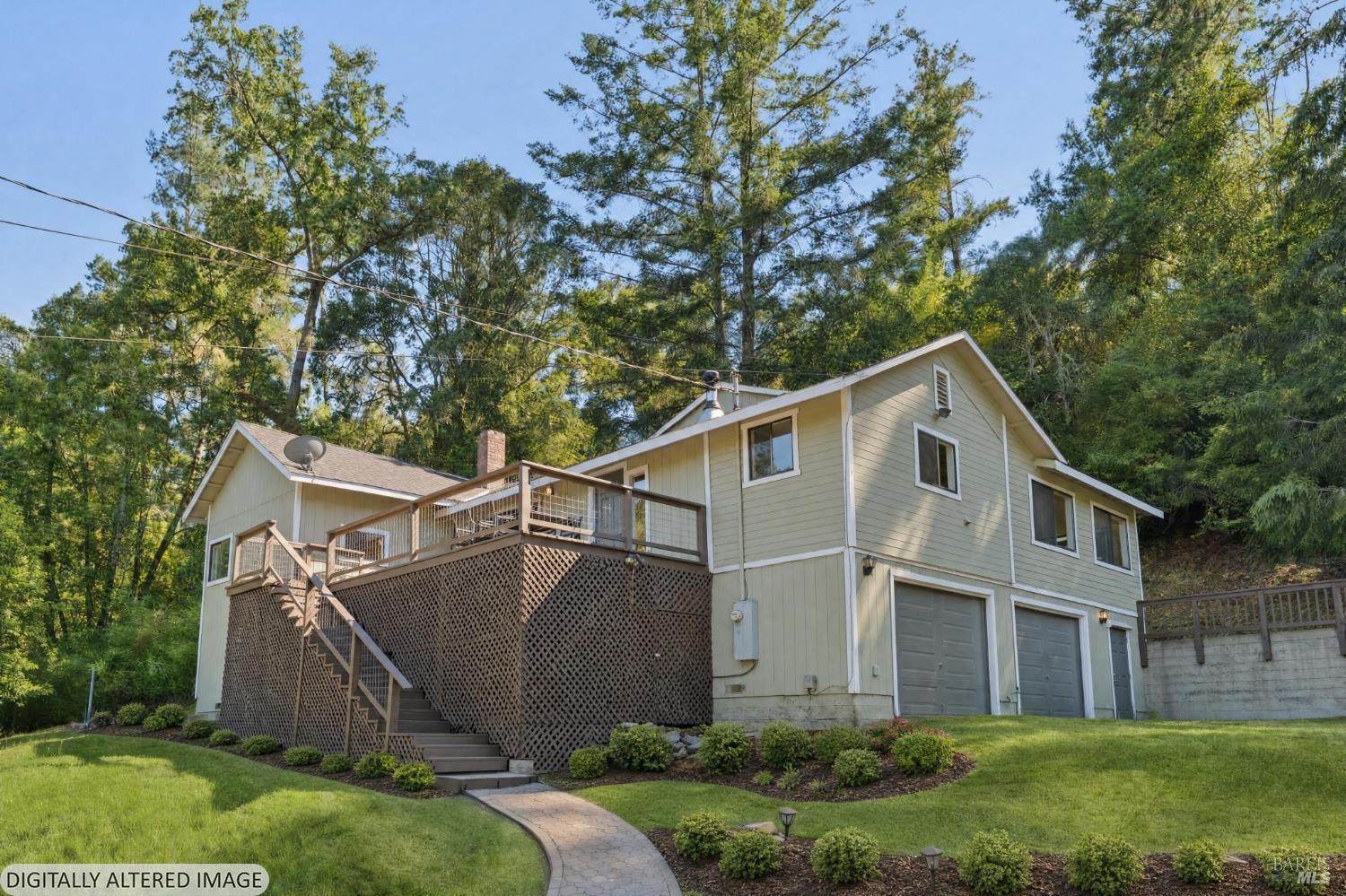 Two-story home with a raised deck and garage, surrounded by tall trees and landscaped lawn.
