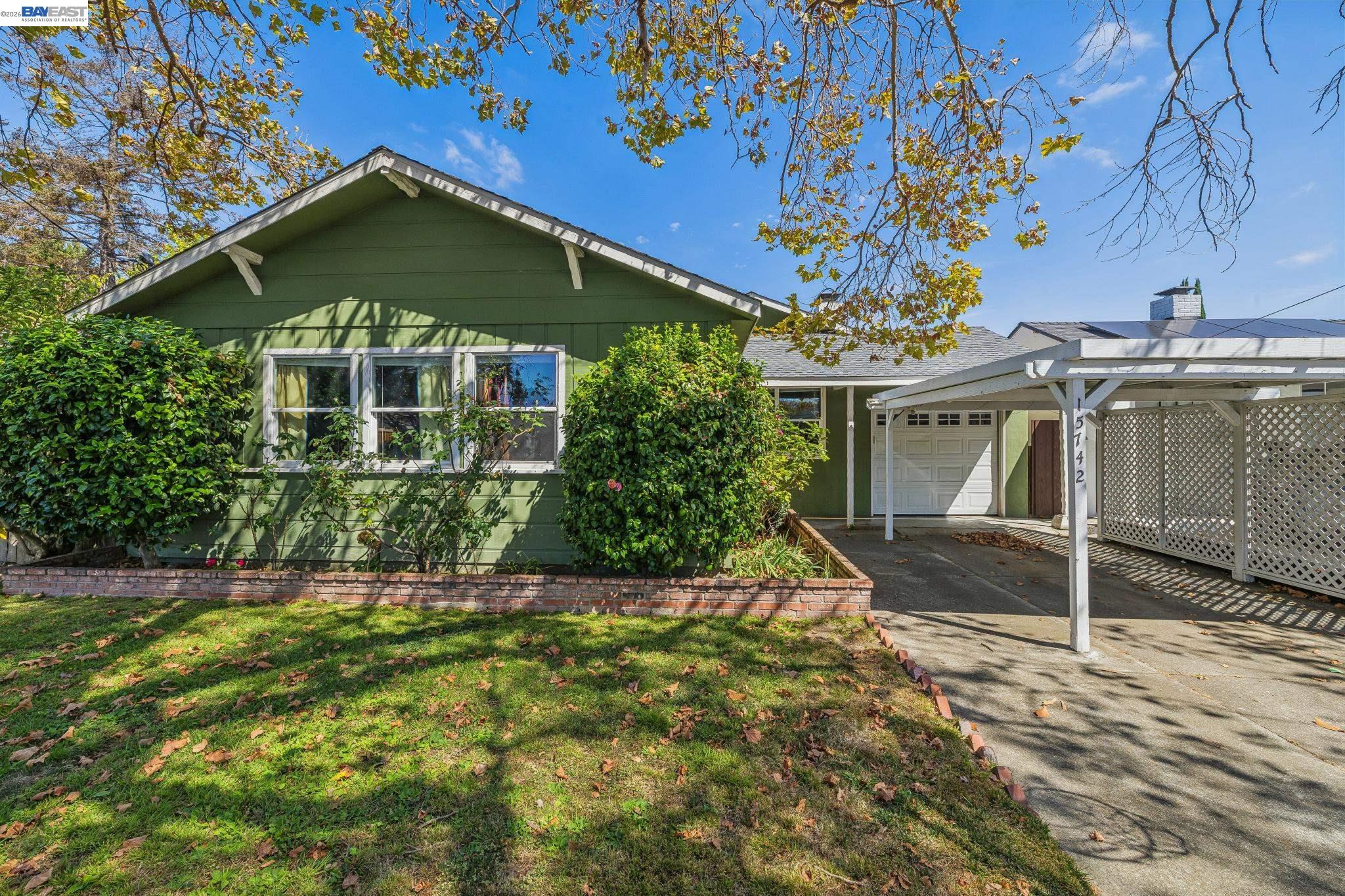 Green single-story home with white trim, a garage, and a covered carport.