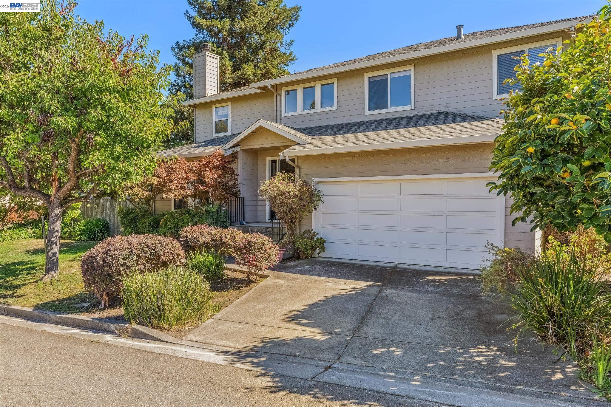 Two-story home with a double garage, landscaped front yard, and fruit-bearing citrus tree.