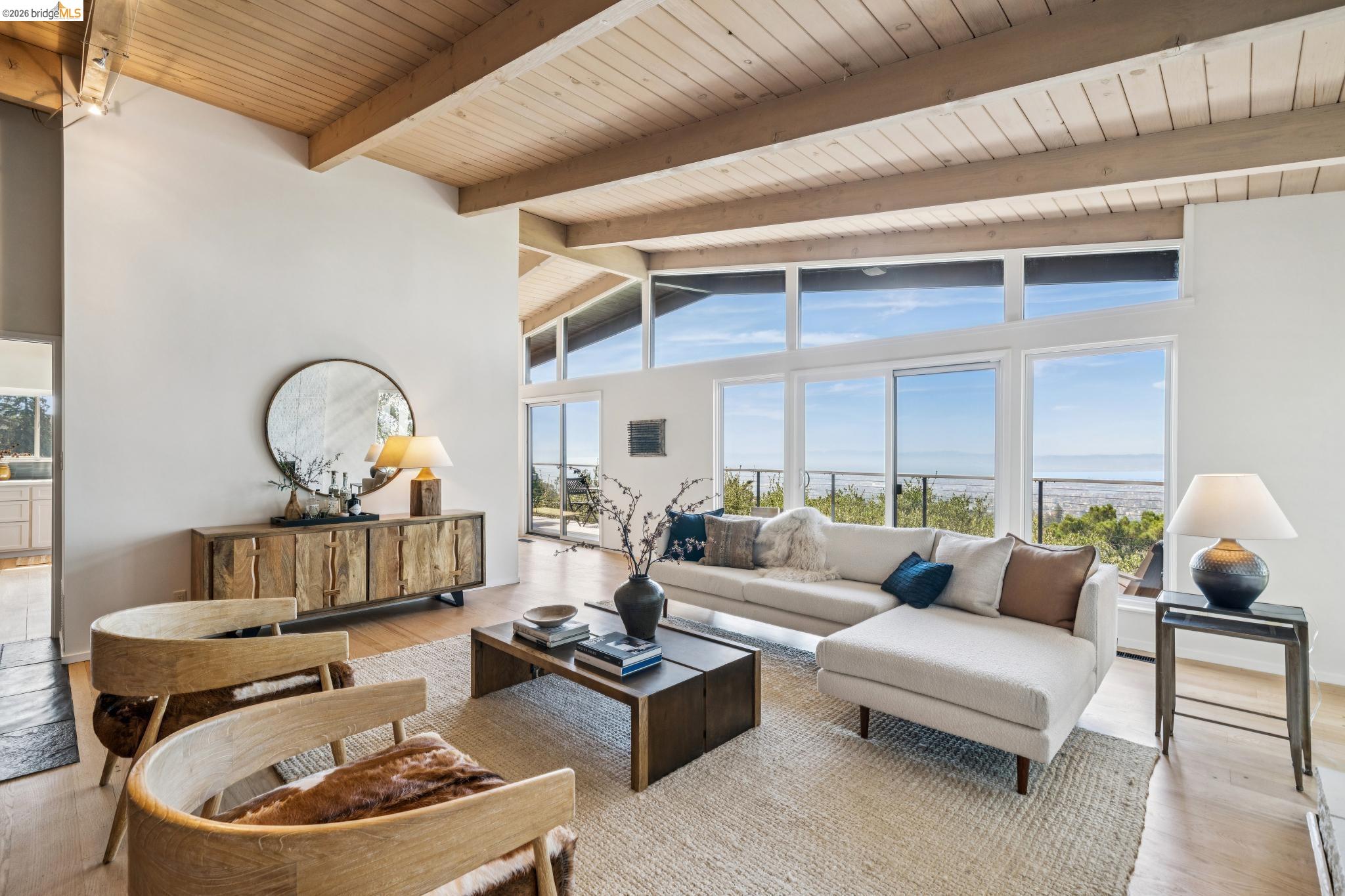 Living room with a vaulted wood ceiling, white sectional, and expansive windows overlooking the water.