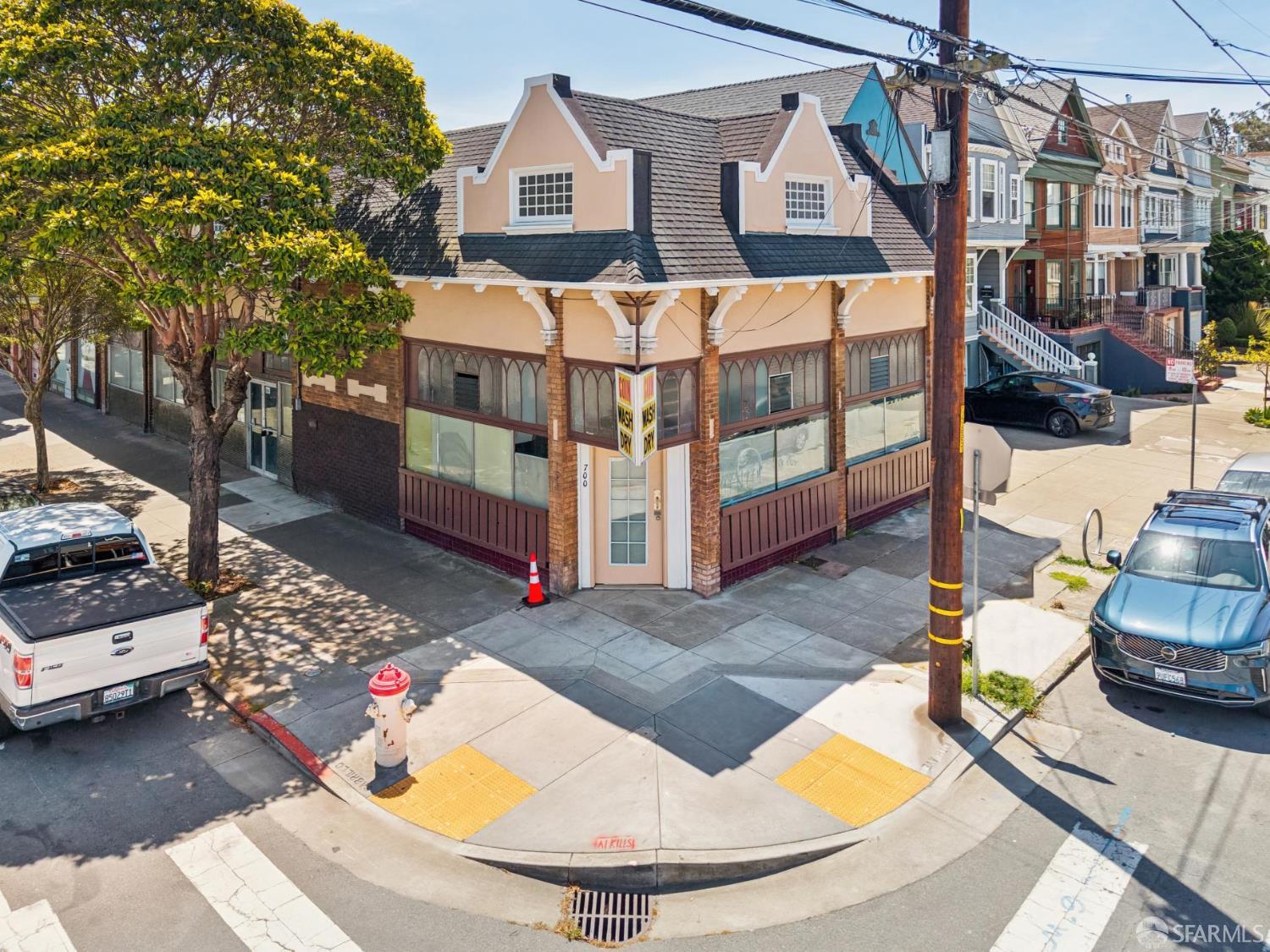 Peach-colored corner commercial building with large storefront windows and decorative gables.