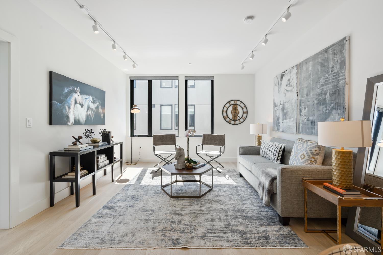 Living room with a gray sofa, patterned rug, and tall windows.