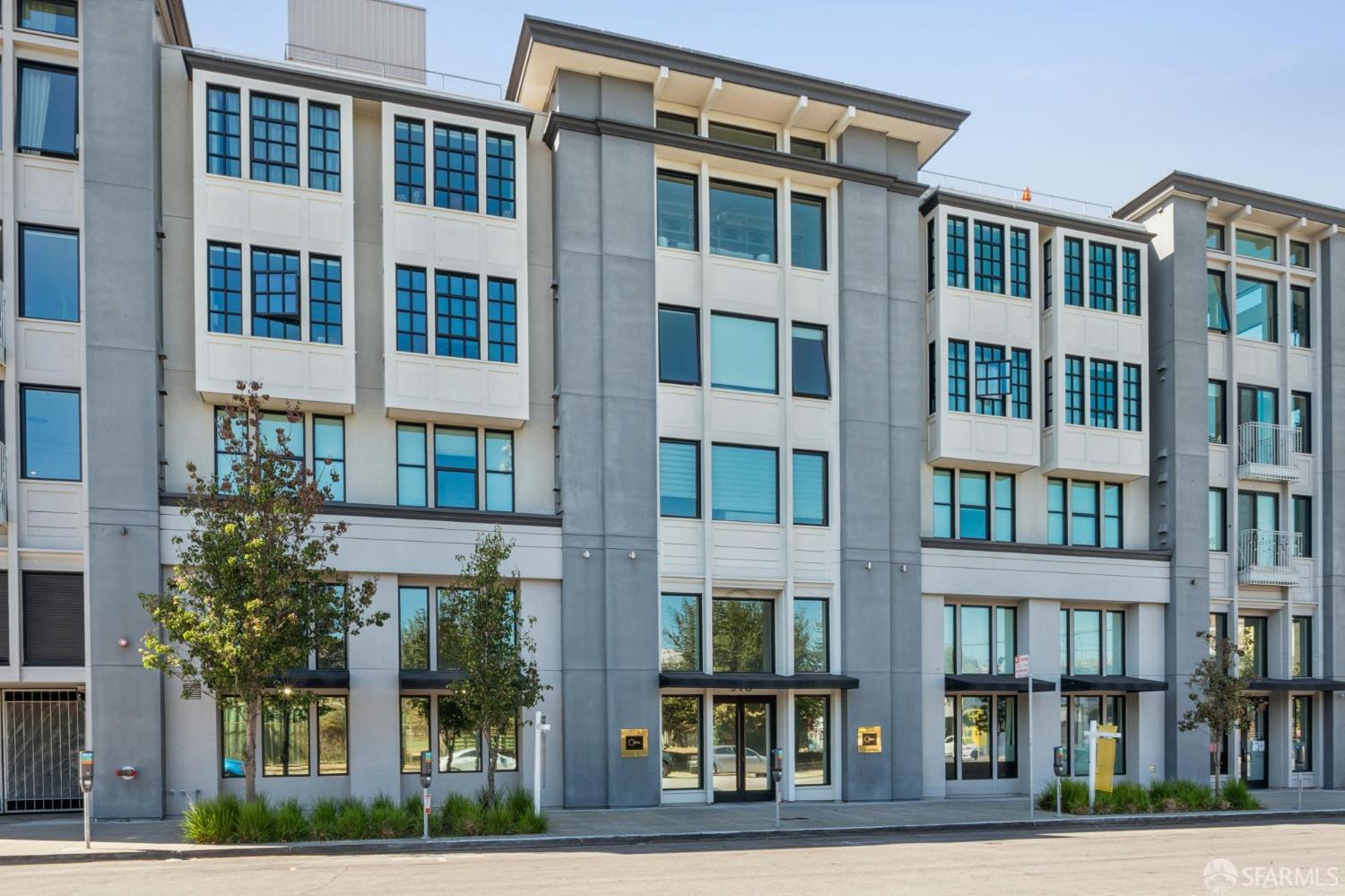 Modern multi-story residential building with a gray-and-white facade and rows of large windows.