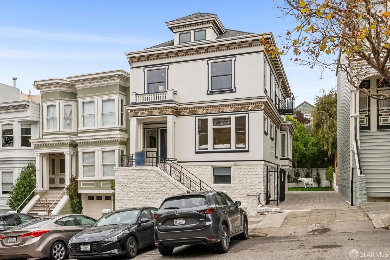 Cream San Francisco home with dark trim, stone lower level, and ornate front staircase.