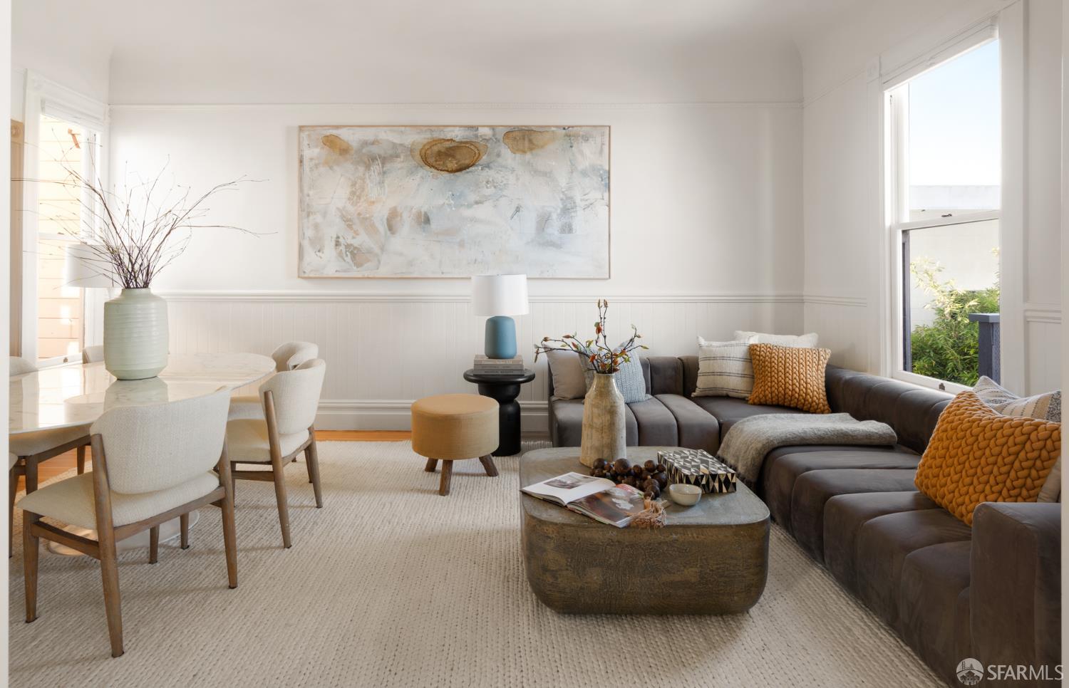 Living and dining room with a gray sectional, round dining table, and large abstract artwork.