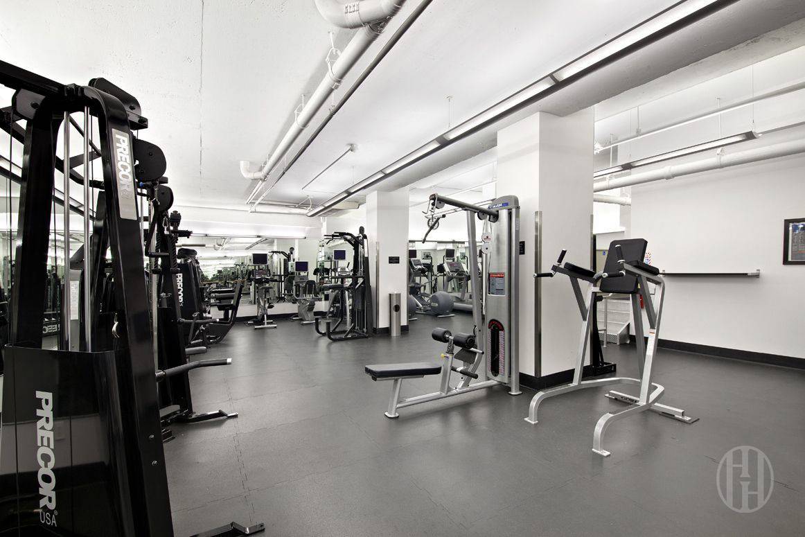 Fitness center with rows of strength-training machines and mirrored walls.