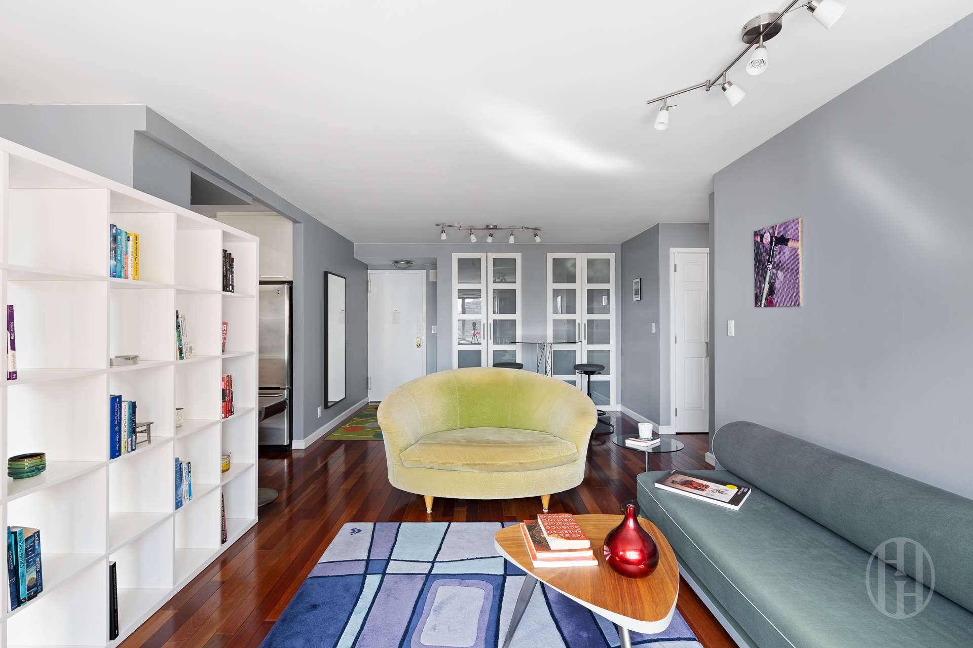 Furnished living room with built-in bookshelves, a yellow chair, and dark hardwood floors.