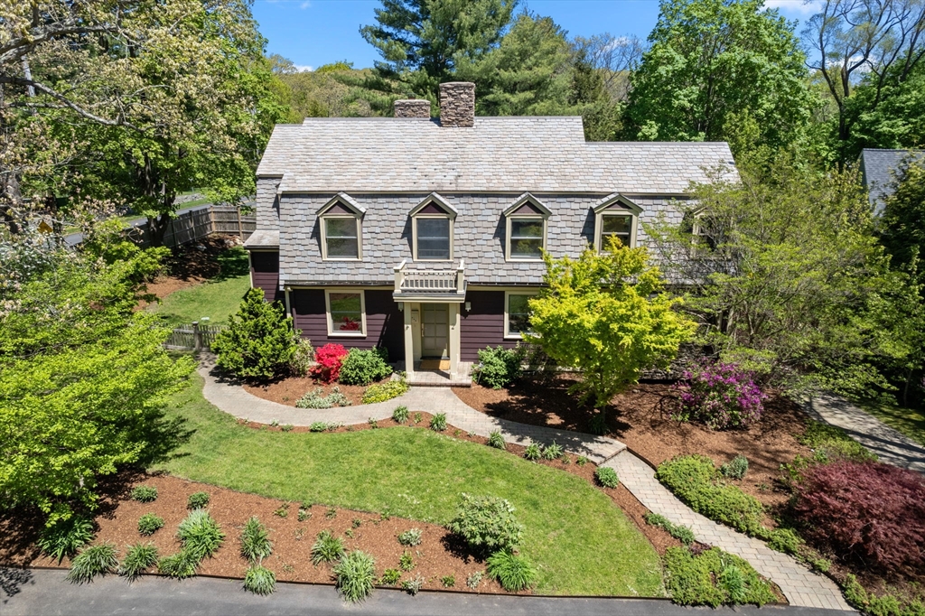 Two-story home with four dormers, landscaped gardens, and a curved front walkway.