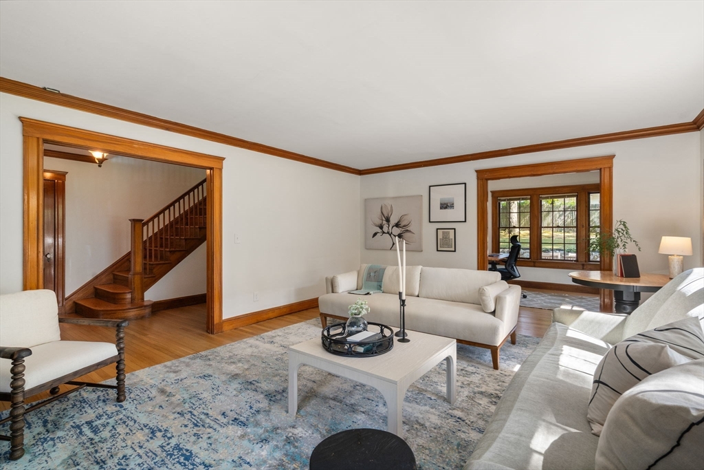 Living room with white sofas, a blue patterned rug, rich wood trim, and an open view of the staircase.