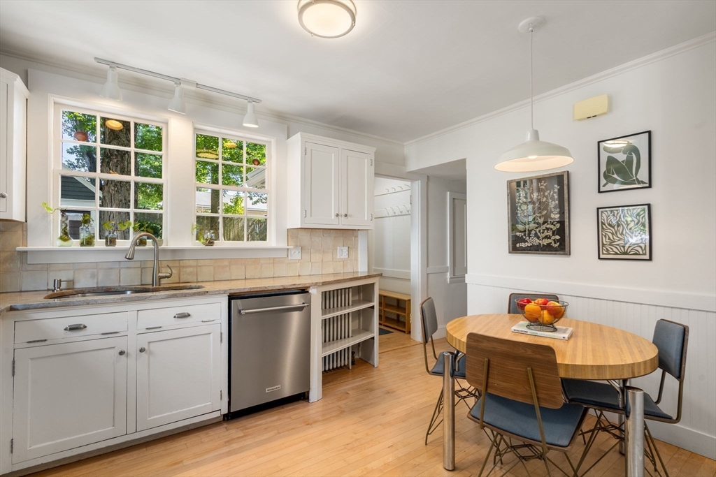 Kitchen with white cabinets, a sink beneath two windows, and an oval dining table.