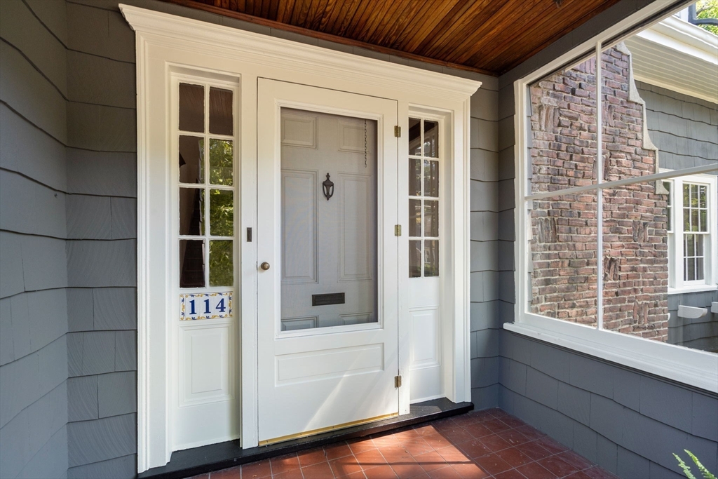 Covered front entrance with white door, sidelights, and 114 address plaque.