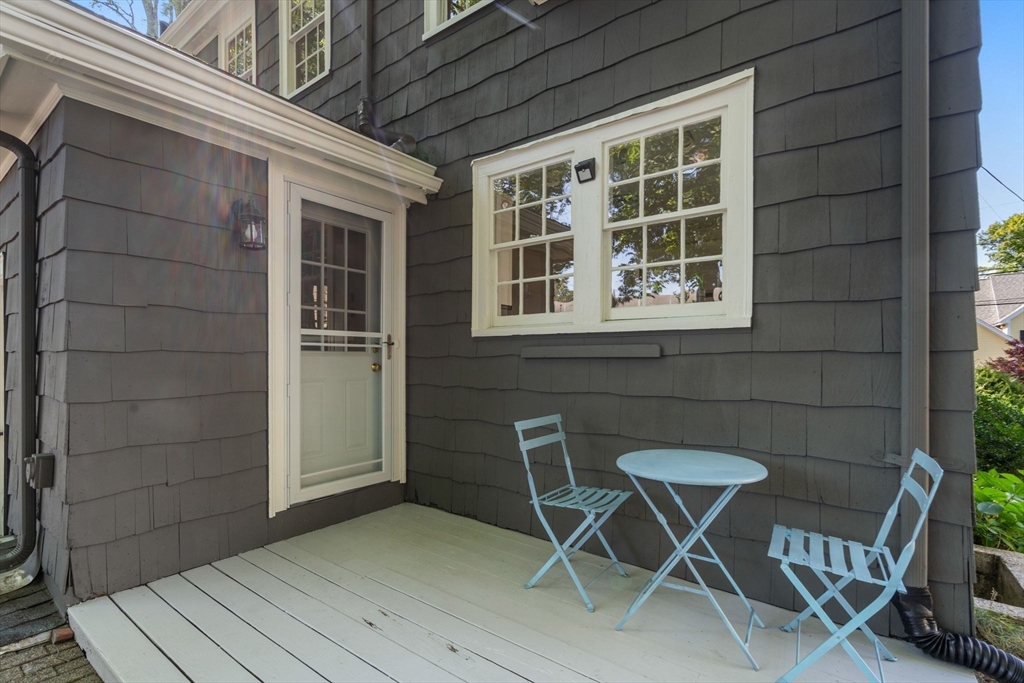 Small porch with pale blue table and chairs beside a white-trimmed glass door.